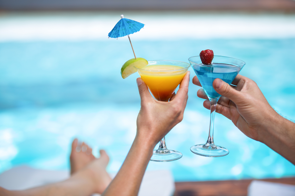 Hands,of,couple,toasting,martini,glass,near,pool